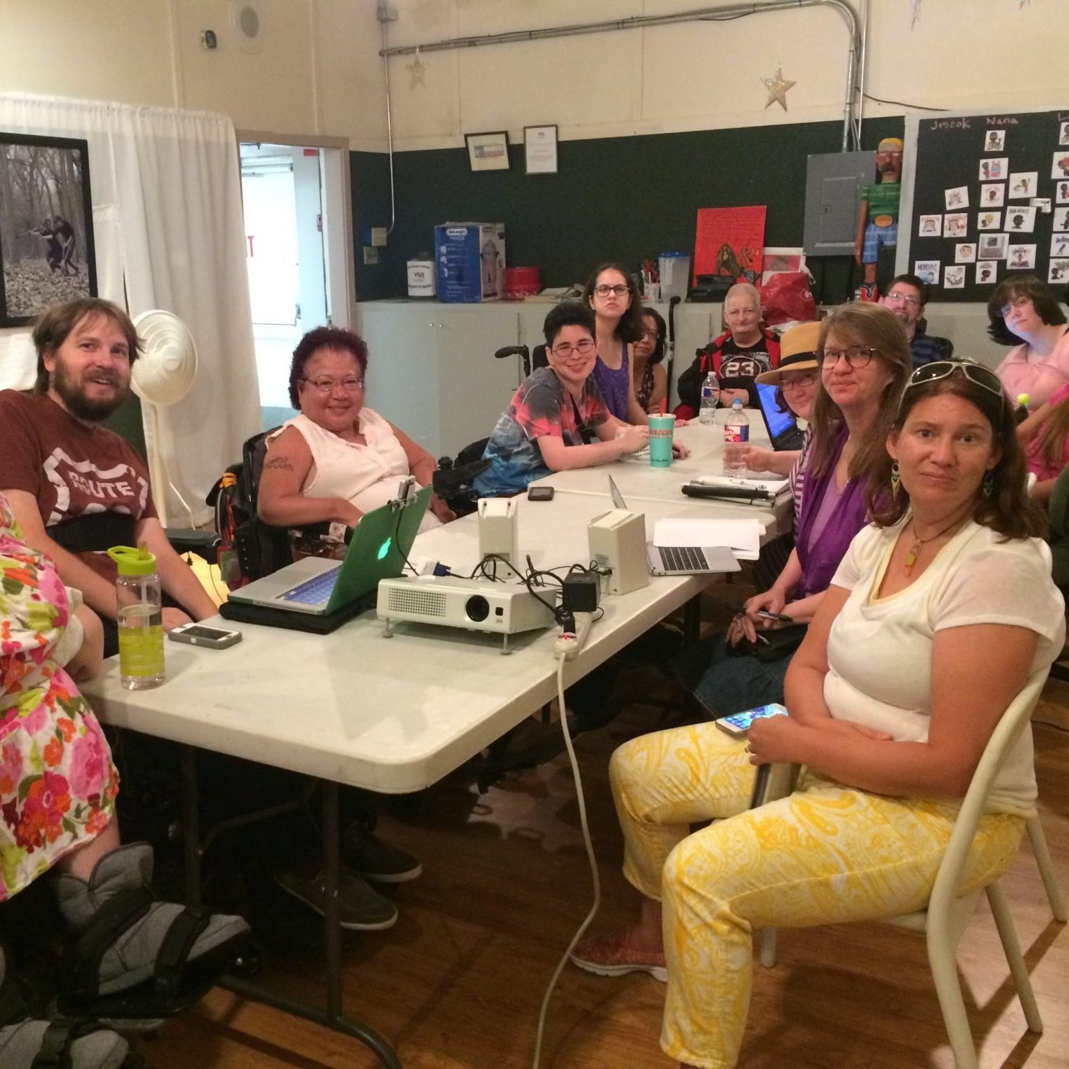 A dozen OMOD participants seated at a long table pose for a photo